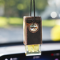 Car air freshener with brown leather cover hanging from a car's rearview mirror.